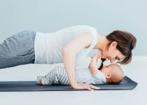 young mother does physical yoga exercises together with her baby boy
