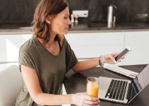 Side vew of casual woman using smartphone, computer and juice